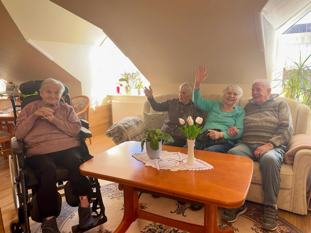 Vier Bewohner sitzen in einem unserer Zimmer schauen glücklich in die Kamera