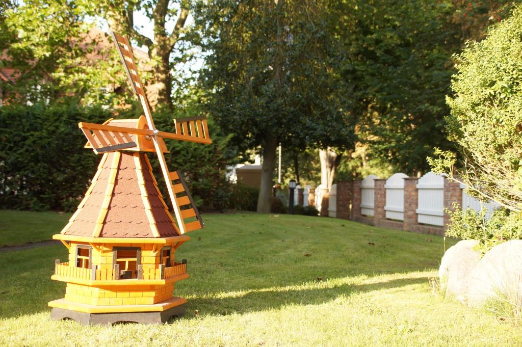 Eine menschengr0ße Holzwindmühle im Garten des Hauses.